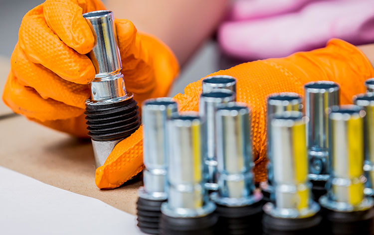 Person with orange gloves holding metal object